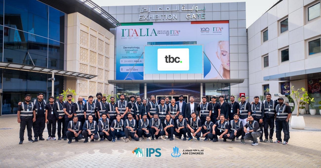The tbc. crew in front of the Exhibition Gate at Dubai World Trade Centre, with the IPS and AIM Congress logos